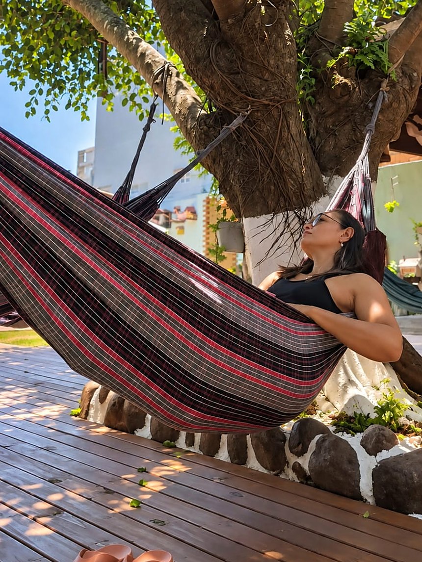 Rede na sombra da árvore, no deck de madeira da pousada